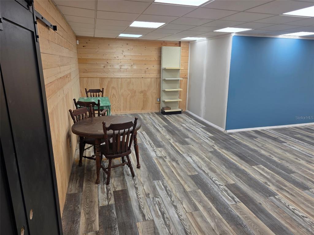A room with wood-paneled walls, a blue accent wall, wood-look flooring, and a dining set — 2001 9TH STREET W, BRADENTON, FL