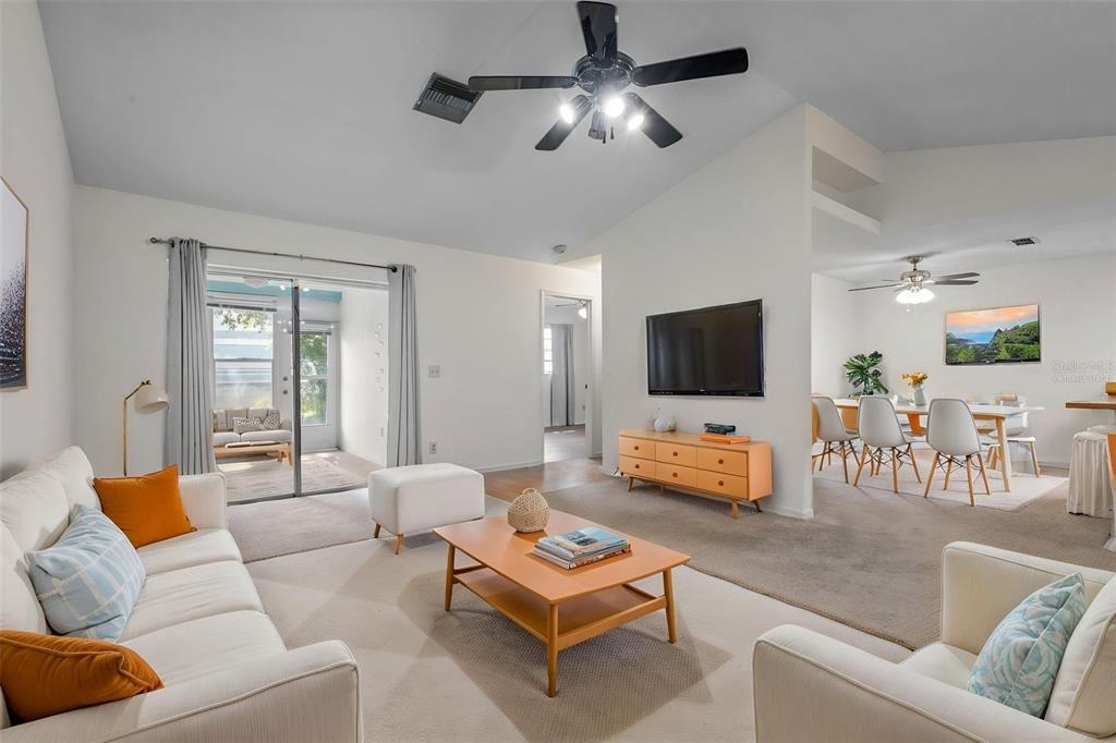 A living room with white sofas, a wooden coffee table, and an adjacent dining area — 3416 CLAIRES COURT, NEW PORT RICHEY, FL