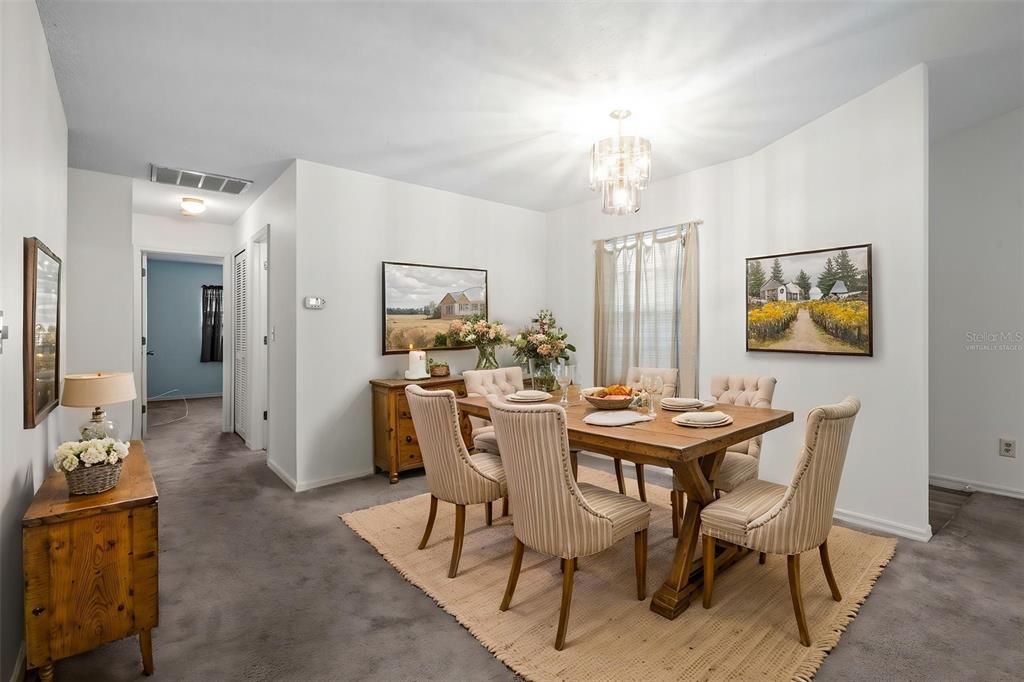 A dining room features a wooden table with six chairs on a textured area rug — 3416 CLAIRES COURT, NEW PORT RICHEY, FL