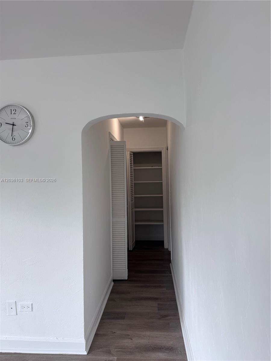 A hallway with an arched entrance leads to a closet with built-in shelving — 1238 NE 110th St # 1, Miami FL 33161, MIAMI, FL