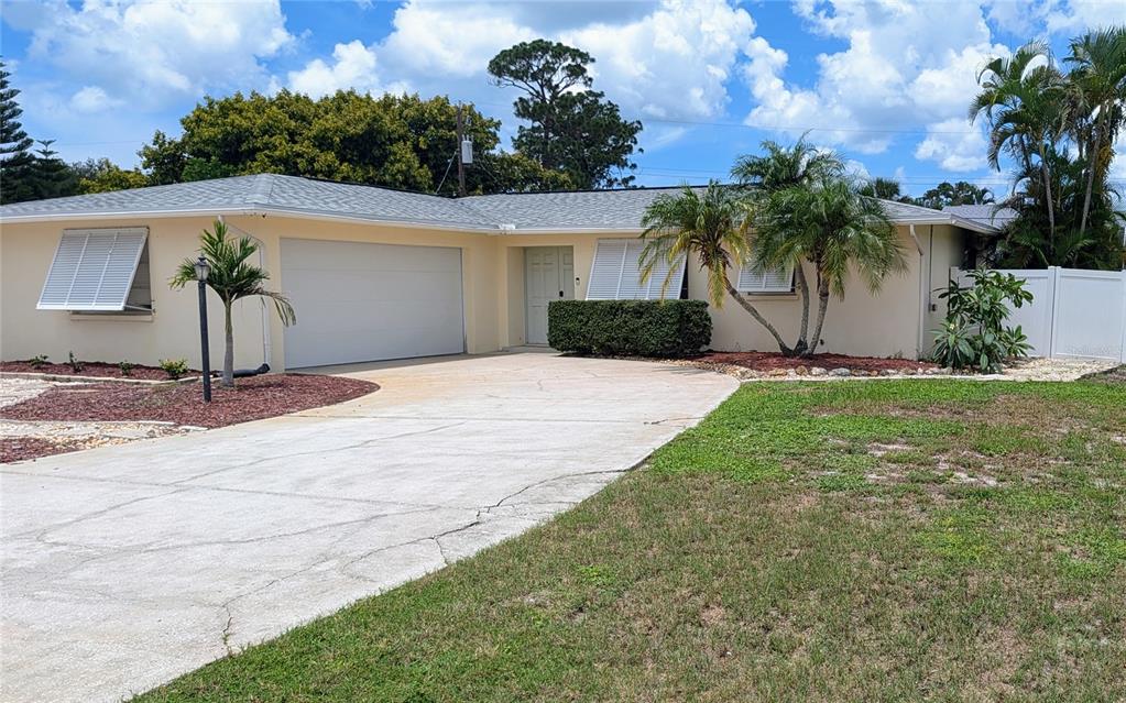 A single-story house with a beige exterior, a two-car garage, and a concrete driveway — 1406 S VENICE BOULEVARD, VENICE, FL