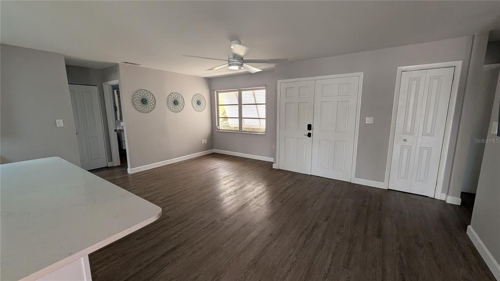 An open living area features gray walls, wood-look flooring, a ceiling fan, and white doors — 1406 S VENICE BOULEVARD, VENICE, FL