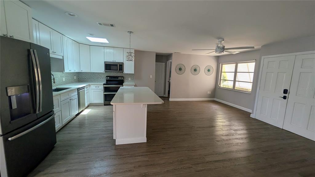 A kitchen with white cabinets, a central island, and wood-look flooring opens to a dining area — 1406 S VENICE BOULEVARD, VENICE, FL