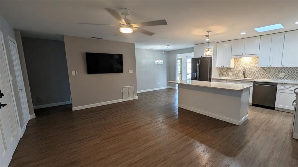 An open-concept kitchen and living area features white cabinetry, a kitchen island, and wood flooring — 1406 S VENICE BOULEVARD, VENICE, FL