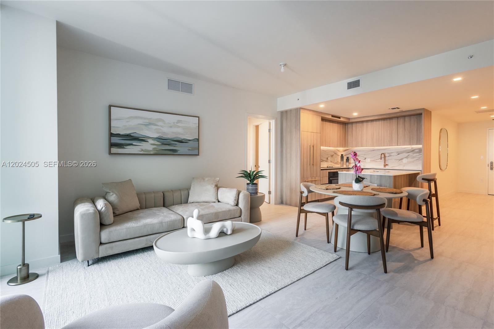 This open-concept living and dining area features light wood cabinetry and neutral-toned modern furniture — 77 SE 5TH STREET # 2602, Miami FL 33131, MIAMI, FL