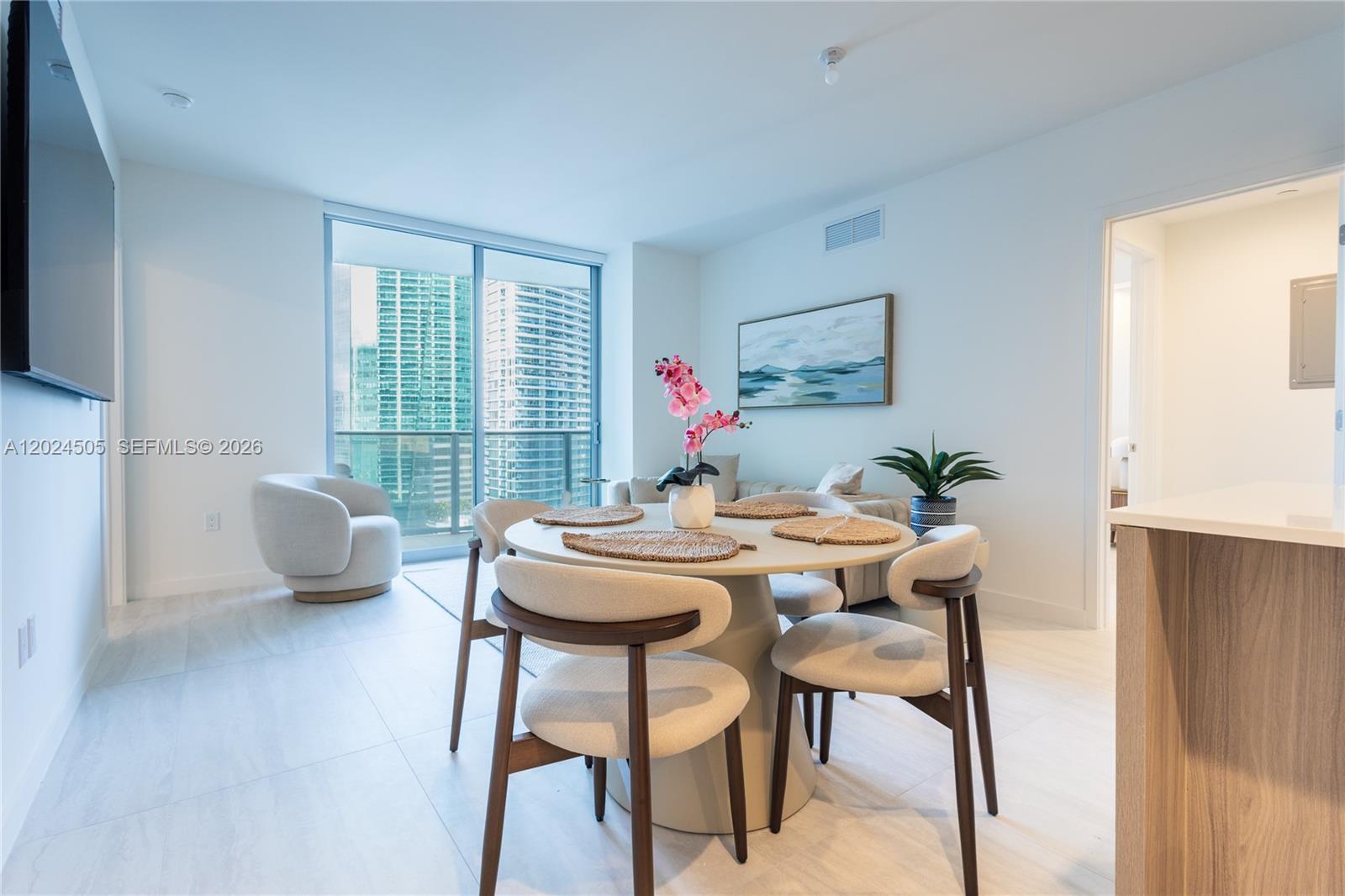 A dining area features a round table with four chairs, light flooring, and balcony views — 77 SE 5TH STREET # 2602, Miami FL 33131, MIAMI, FL