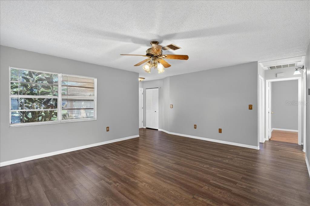 An empty room with gray walls, dark wood-look flooring, and a ceiling fan — 10202 56TH STREET N, PINELLAS PARK, FL