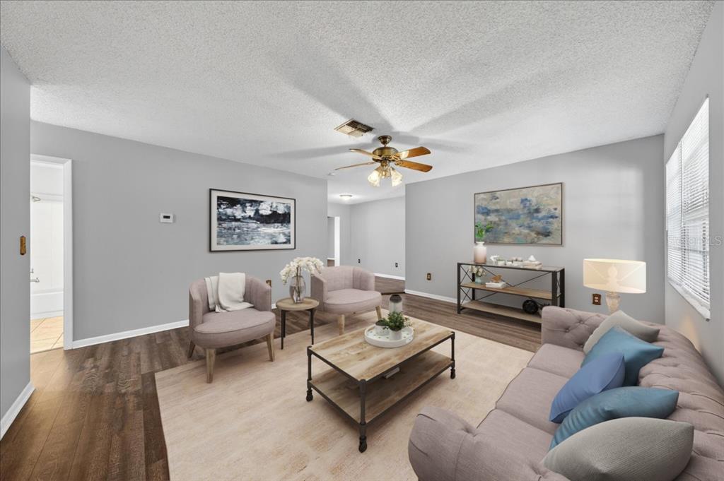A living room features light gray walls, wood-look flooring, a ceiling fan, and neutral furniture — 10202 56TH STREET N, PINELLAS PARK, FL
