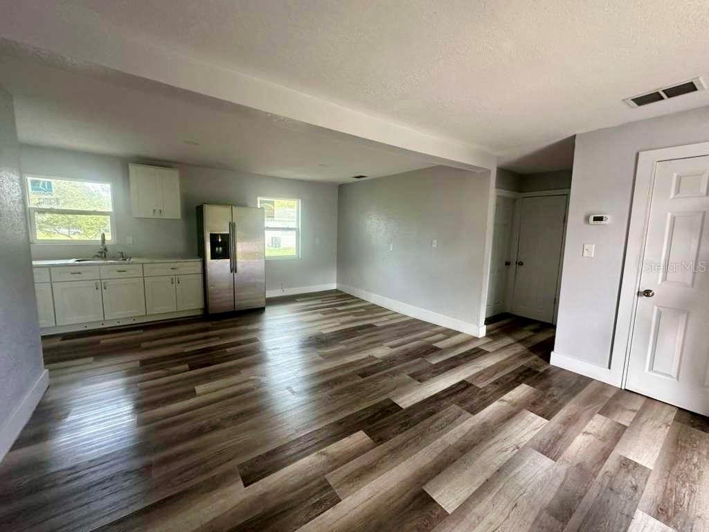 A kitchen and living area feature light gray walls, white cabinets, and wood-look flooring — 1550 E BAY STREET, BARTOW, FL