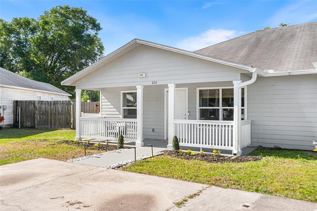 A single-story house with light gray siding, a covered front porch, and a concrete driveway — 608 PINEVILLE LANE, LAKELAND, FL