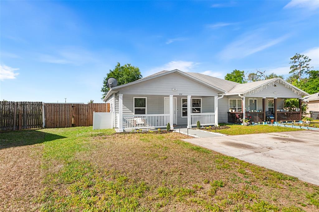 A light gray single-story house features a front porch with white railings and a driveway — 608 PINEVILLE LANE, LAKELAND, FL