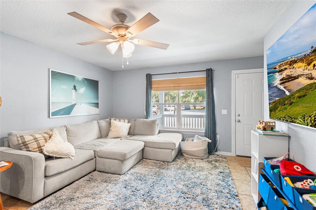 A living room features a sectional sofa, a ceiling fan, and a large wall-mounted television — 608 PINEVILLE LANE, LAKELAND, FL