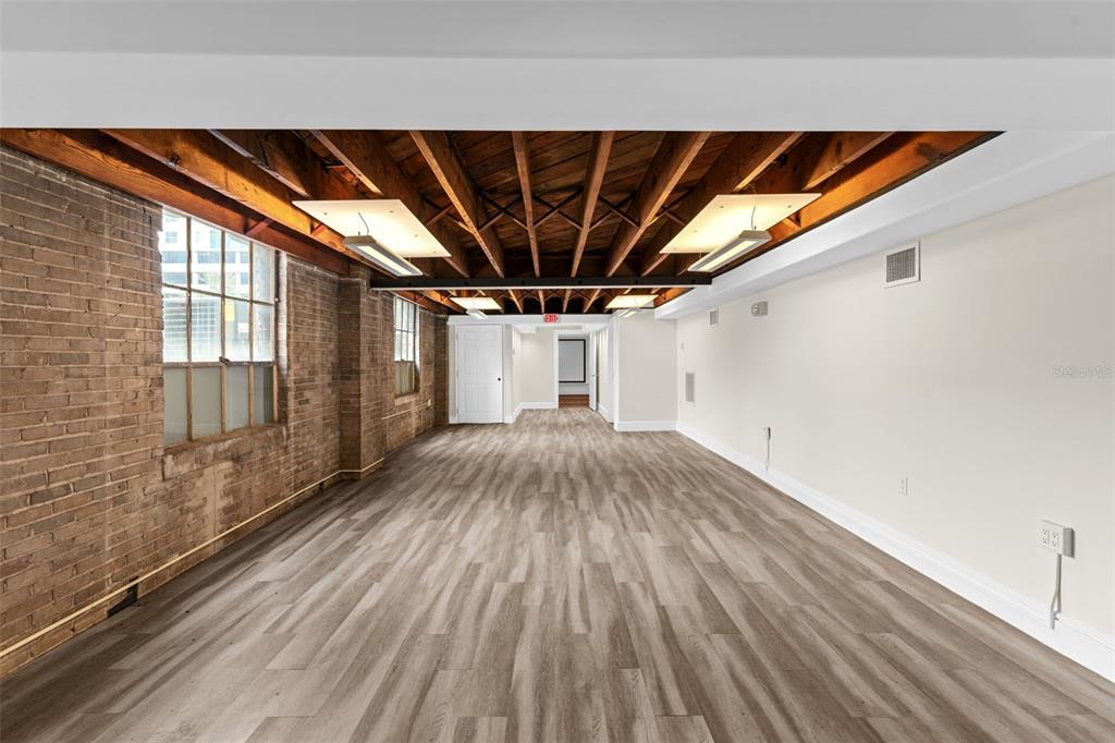 An interior view of a room featuring exposed wooden ceiling beams, brick walls, and flooring — 1121 E TWIGGS STREET 2ND FLR, TAMPA, FL