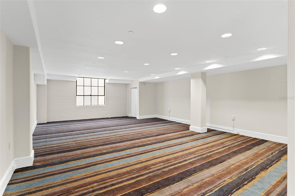 A large, empty room features recessed lighting, a grid-pane window, and striped wall-to-wall carpeting — 1121 E TWIGGS STREET 2ND FLR, TAMPA, FL