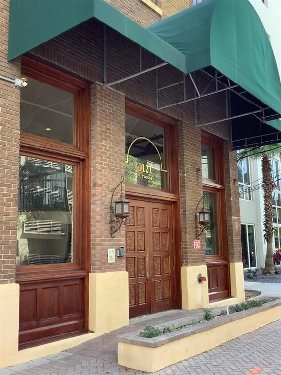 The exterior of a brick building features a green awning over a wooden double door — 1121 E TWIGGS STREET 2ND FLR, TAMPA, FL