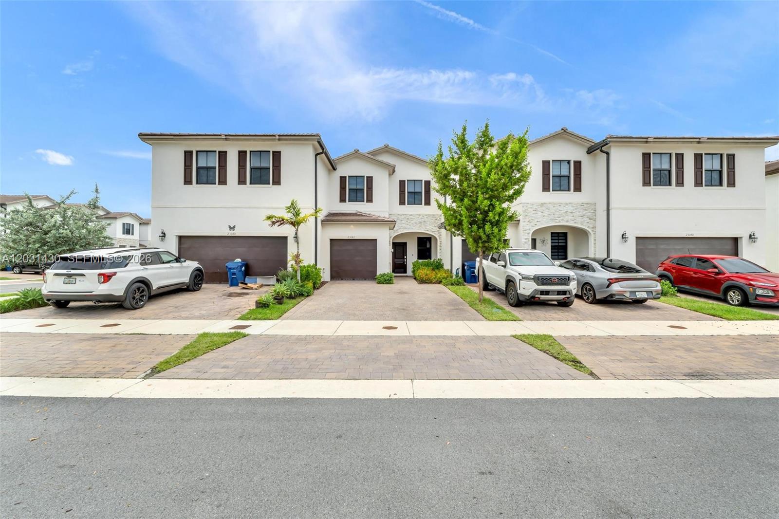 A row of three two-story townhouses with paved driveways and parked cars under a sky — 23082 SW 129th Ct # 23082, Miami FL 33170, MIAMI, FL