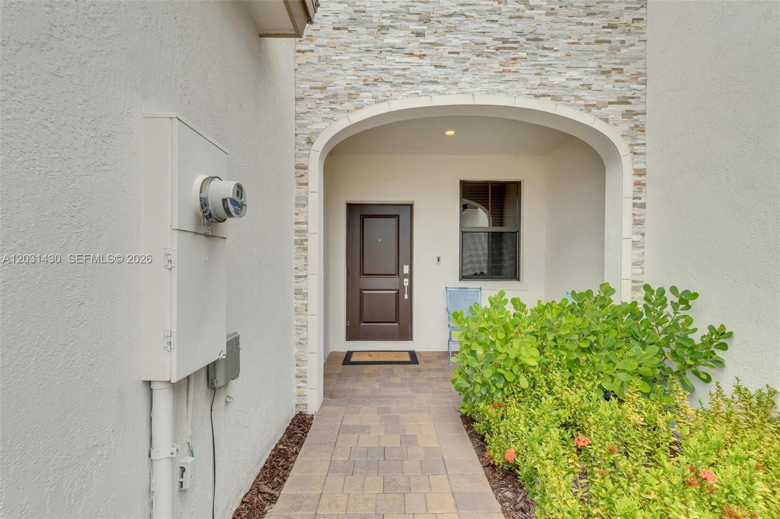 A paved walkway leads to a front door recessed under a stone-accented arched entryway — 23082 SW 129th Ct # 23082, Miami FL 33170, MIAMI, FL