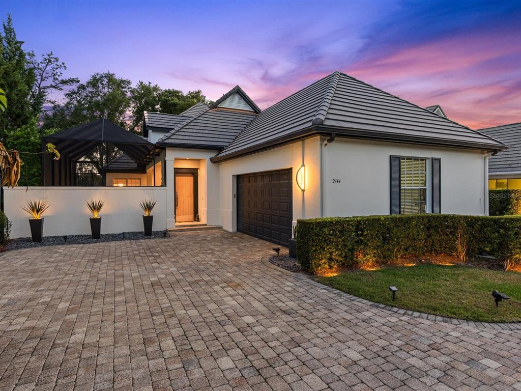 A single-story house with a paved driveway, a dark garage door, and a screened-in patio — 9744 COVENT GARDEN DRIVE, ORLANDO, FL