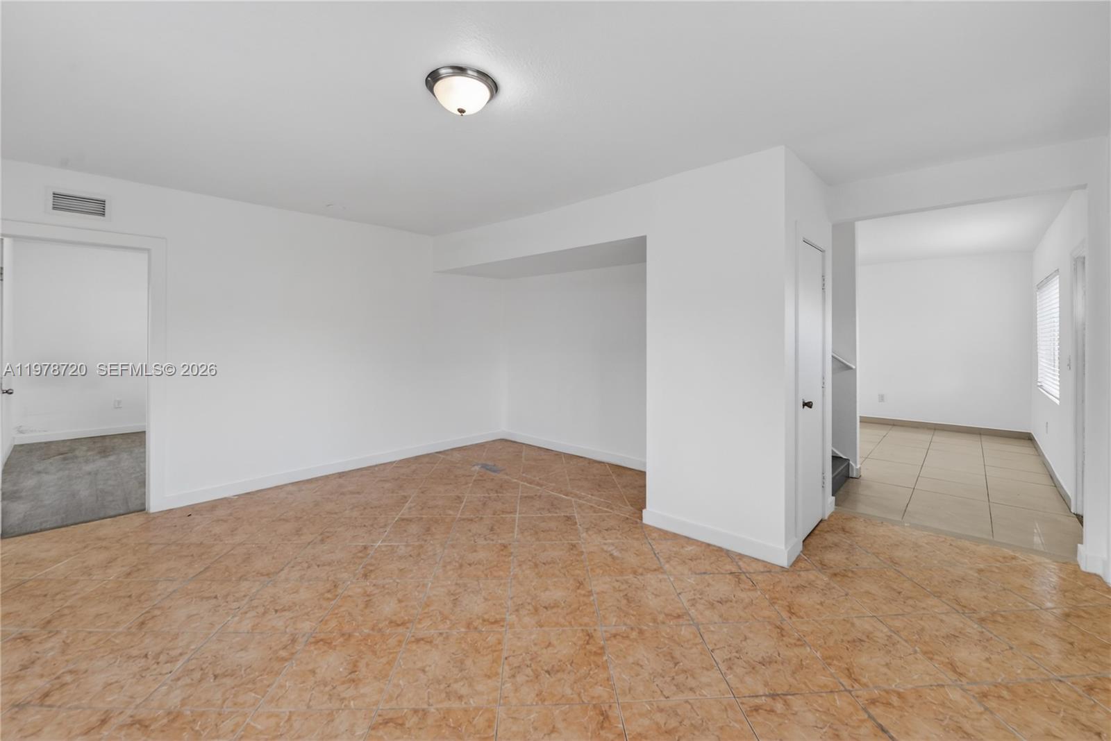 An empty room features white walls, a flush-mount light fixture, and tan tiled flooring — 475 NW 84th Ter # 475, Miami FL 33150, MIAMI, FL