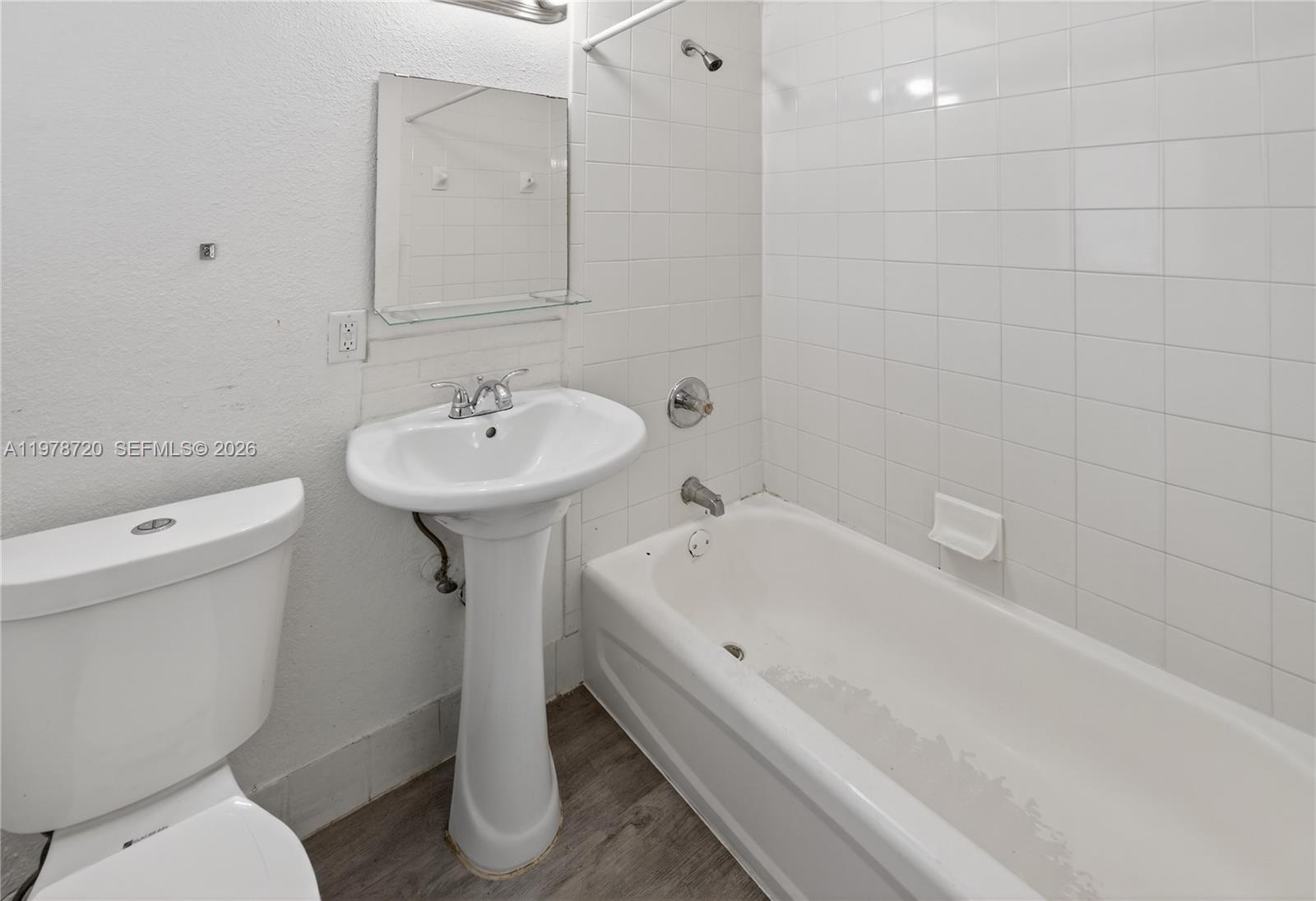 A bathroom features a pedestal sink, a white toilet, and a tiled bathtub shower combo — 475 NW 84th Ter # 475, Miami FL 33150, MIAMI, FL