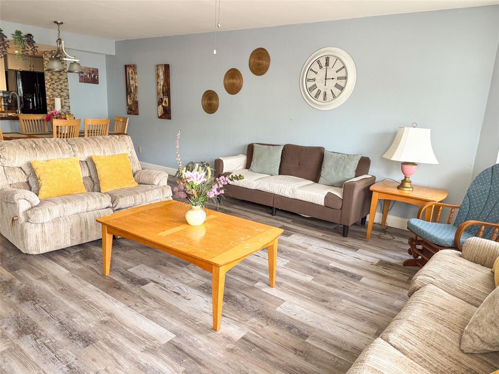 A living room features light blue walls, wood-look flooring, two sofas, a coffee table, and a clock — 2731 N POINCIANA BOULEVARD UNIT 105, KISSIMMEE, FL