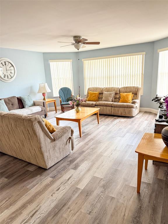 A living room features light blue walls, wood-look flooring, a ceiling fan, and beige furniture — 2731 N POINCIANA BOULEVARD UNIT 105, KISSIMMEE, FL