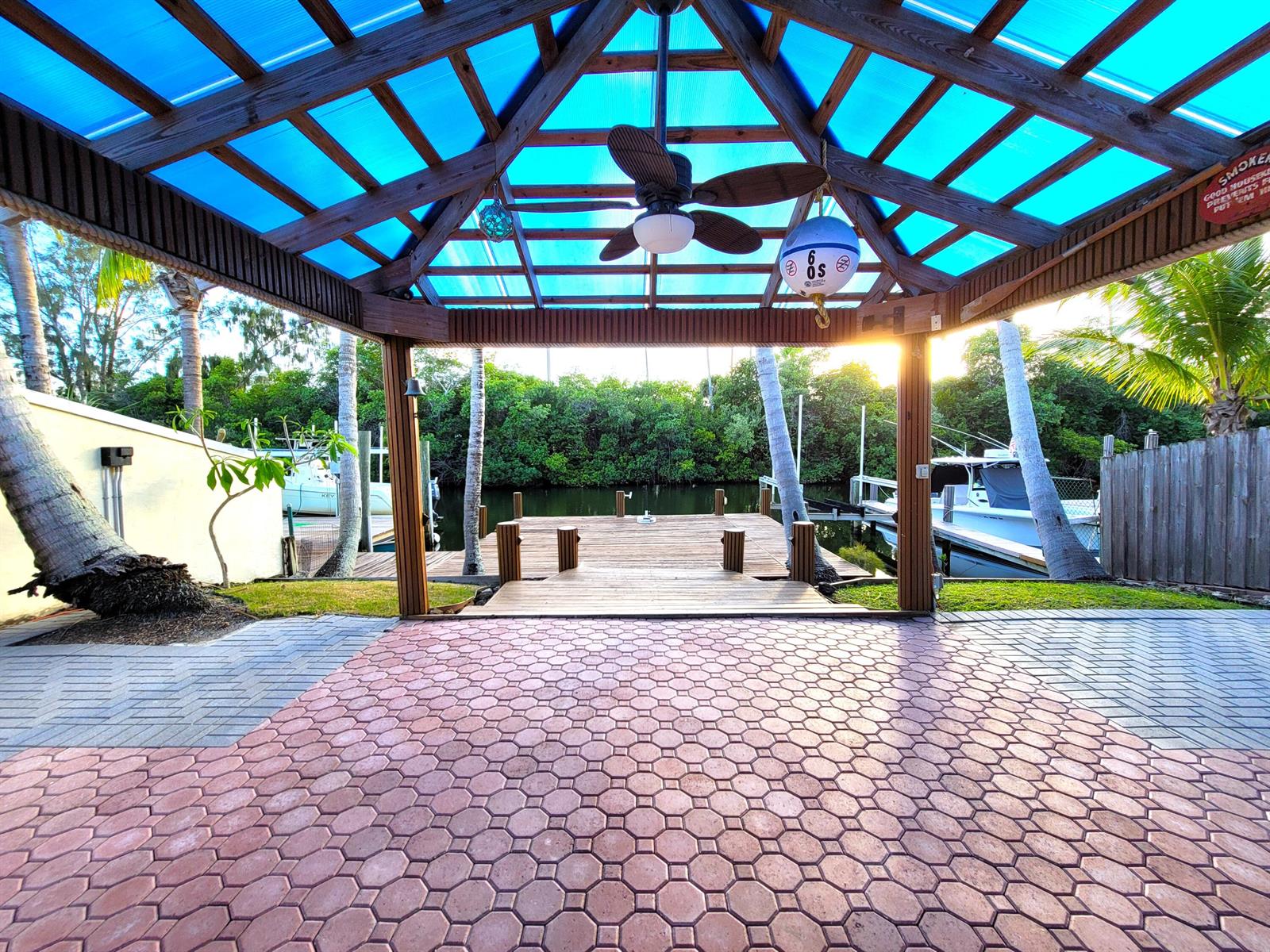 A covered outdoor patio with a wooden ceiling and ceiling fan overlooks a boat dock — 1903 Robalo Drive, Vero Beach FL 32960, VERO BEACH, FL