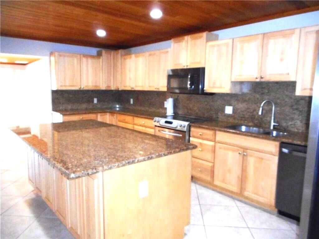 A kitchen with light wood cabinets, granite countertops, a center island, and wood-paneled ceiling — 1903 Robalo Drive, Vero Beach FL 32960, VERO BEACH, FL