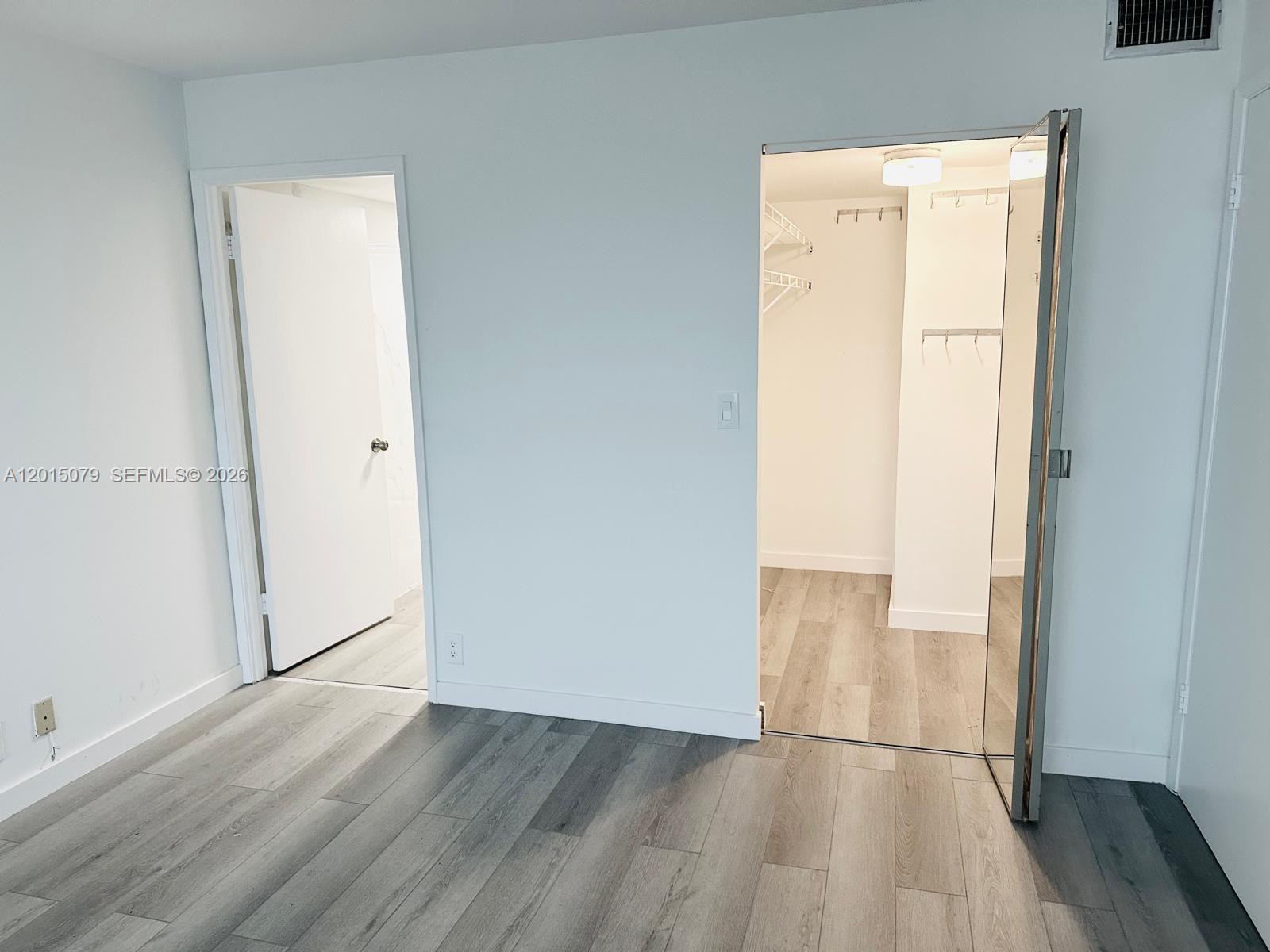 A room with gray wood-look flooring features a doorway to a bathroom and a closet — 1901 Brickell Ave # B2104, Miami FL 33129, MIAMI, FL