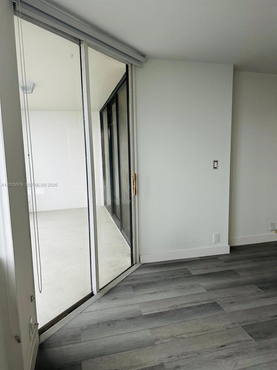 A room with gray wood-look flooring features a sliding glass door leading to a balcony — 1901 Brickell Ave # B2104, Miami FL 33129, MIAMI, FL