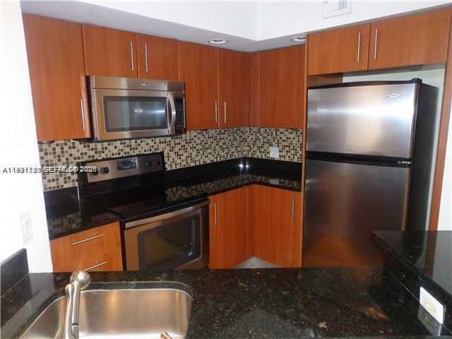 A kitchen features wood cabinets, stainless steel appliances, a mosaic tile backsplash, and granite countertops — 3300 N Pinewalk Dr N # 1928, Margate FL 33063, MARGATE, FL