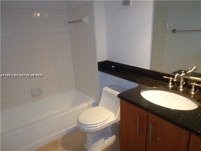 A bathroom features a white bathtub, a toilet, and a vanity with a dark countertop — 3300 N Pinewalk Dr N # 1928, Margate FL 33063, MARGATE, FL