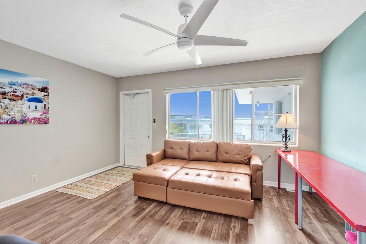 A living room features a brown leather sofa, a red desk, and a ceiling fan — 3120 Cynthia Lane # 207, FL 33461, FL