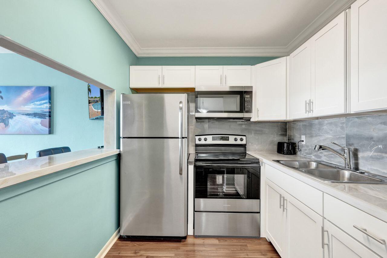 A kitchen with stainless steel appliances, white cabinets, and light blue walls — 3120 Cynthia Lane # 207, FL 33461, FL