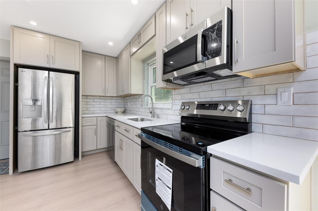 A kitchen with light gray cabinets, stainless steel appliances, white countertops, and a subway tile backsplash — 5621 NW 29TH TERRACE, GAINESVILLE, FL