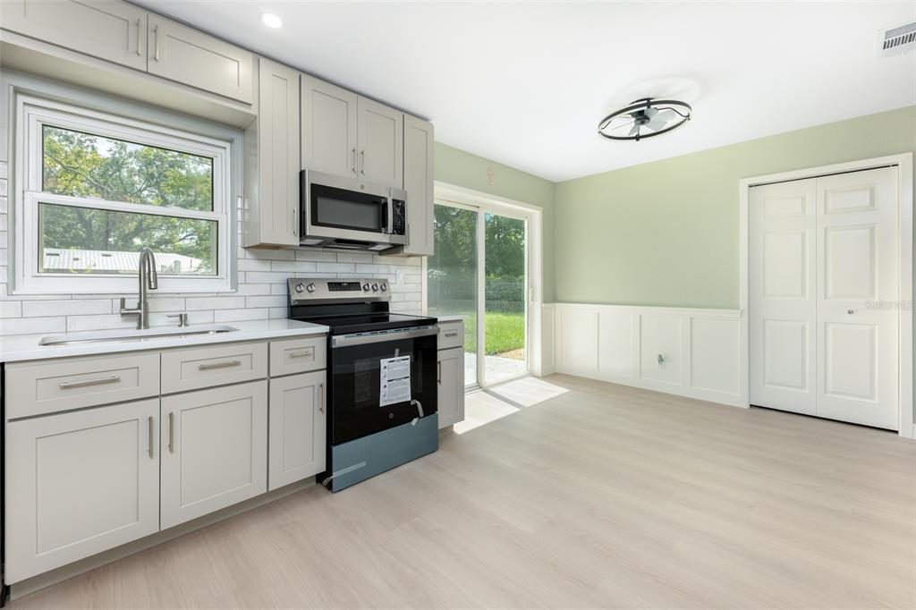 A kitchen with light gray cabinets, stainless steel appliances, and a sliding glass door — 5621 NW 29TH TERRACE, GAINESVILLE, FL