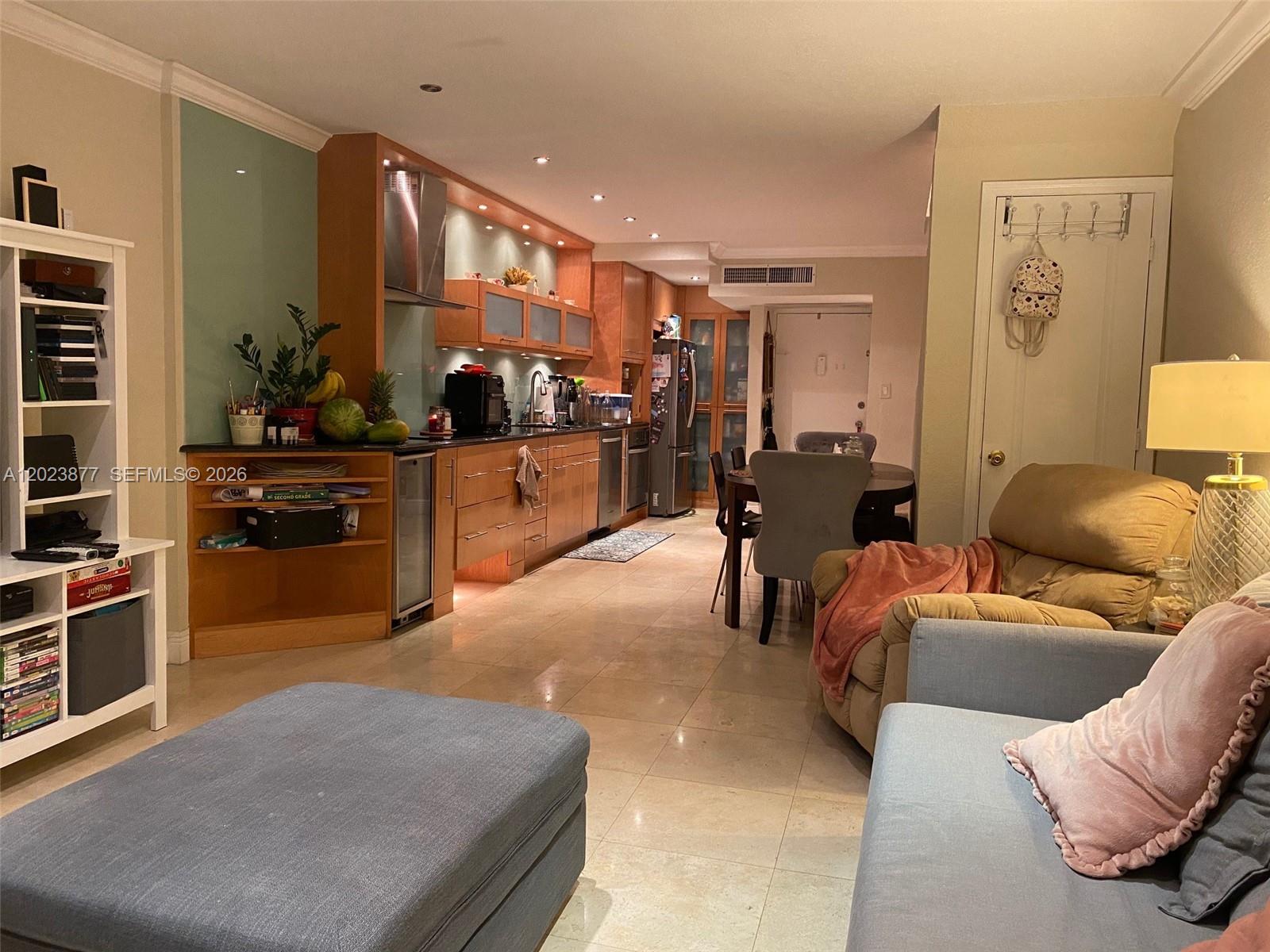 An open-concept living area features a kitchen with wood cabinets and a dining space — 5401 Collins Ave # 339, Miami Beach FL 33140, MIAMI BEACH, FL