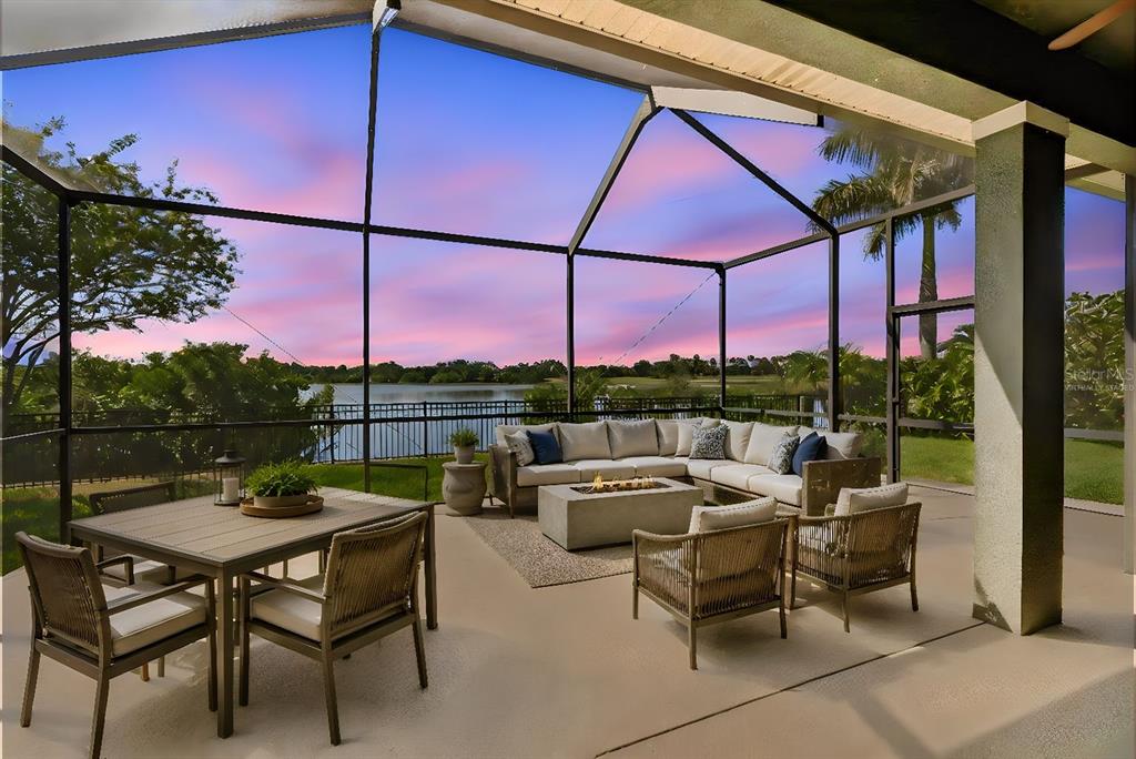 A screened-in patio features outdoor furniture, a fire pit, and a view of a lake — 7223 HOURGLASS DRIVE, APOLLO BEACH, FL