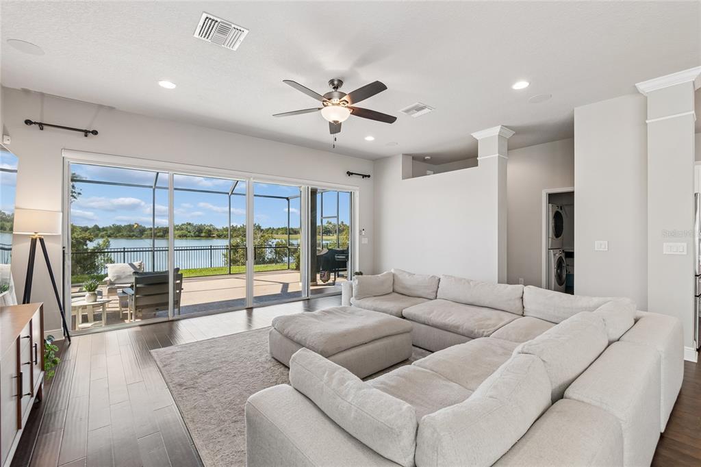 A living room with a large sectional sofa, dark wood floors, and sliding glass doors — 7223 HOURGLASS DRIVE, APOLLO BEACH, FL