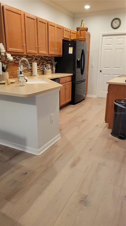 A kitchen features light wood cabinets, a black refrigerator, and light-colored wood flooring — 3716 82ND AVENUE CIRCLE E UNIT 101, SARASOTA, FL