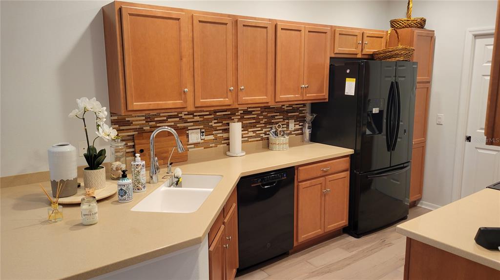 A kitchen features light wood cabinets, a tan countertop, a white sink, and black appliances — 3716 82ND AVENUE CIRCLE E UNIT 101, SARASOTA, FL