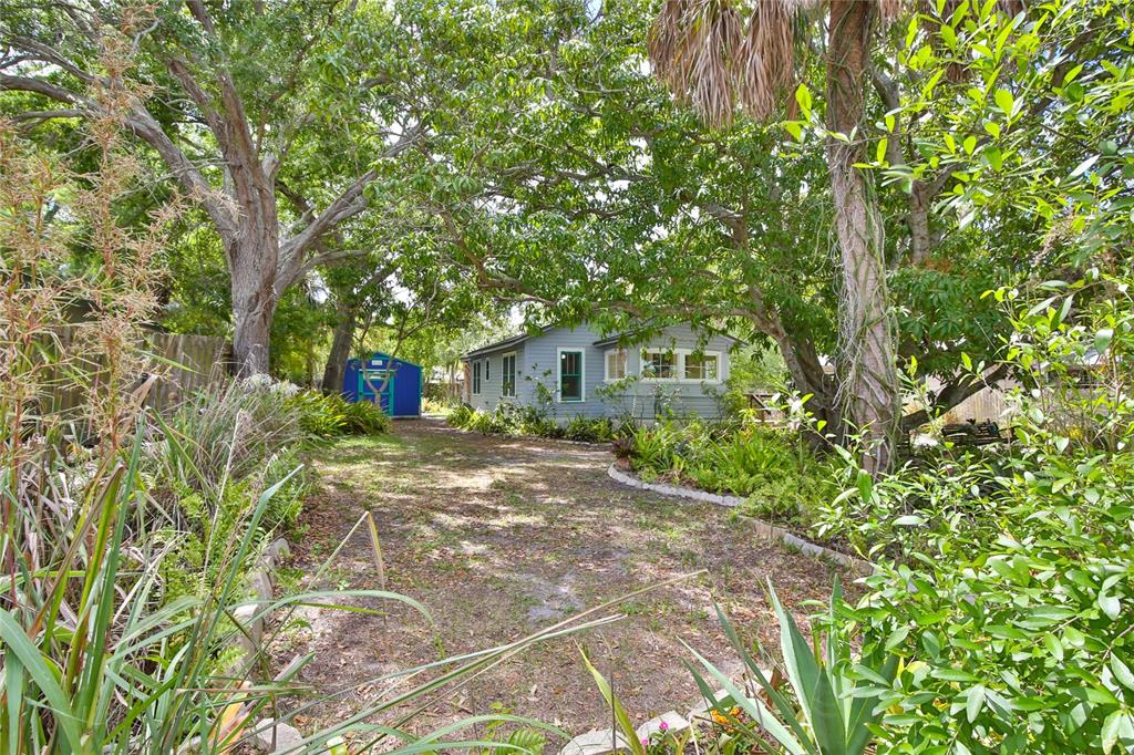 A gray house with a blue shed sits in a yard surrounded by mature trees — 708 42ND STREET, SARASOTA, FL