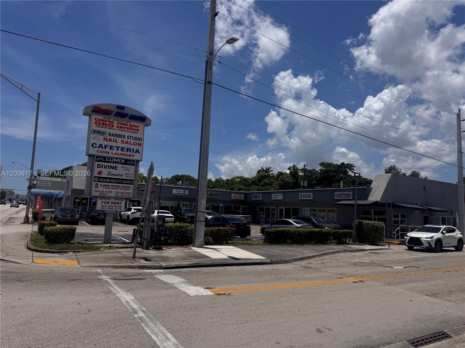 A commercial strip mall with a prominent signage pylon stands under a bright blue sky — 108 SW 27th ave, Miami FL 33135, MIAMI, FL