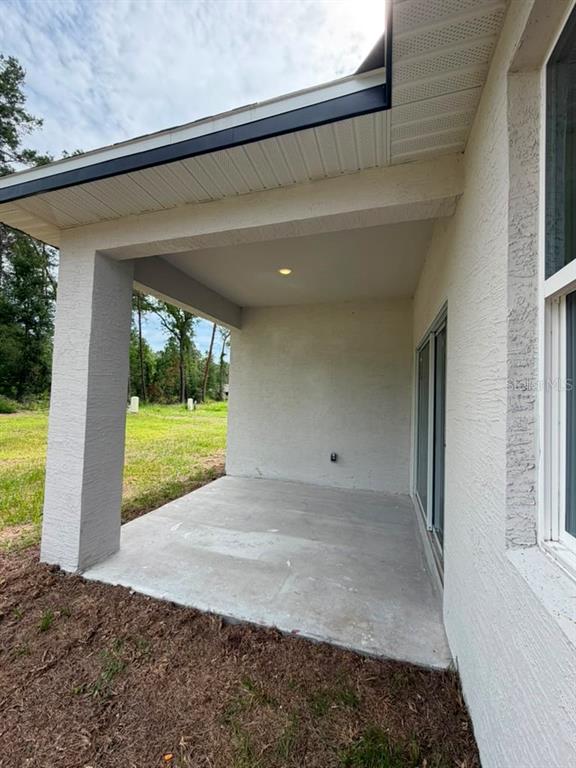 A covered concrete patio is attached to the side of a stucco house — 7939 SW 141ST PLACE, OCALA, FL