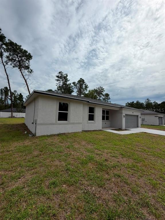 A light-colored, single-story house with a garage sits on a grassy lot under a cloudy sky — 7939 SW 141ST PLACE, OCALA, FL