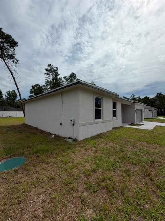 The exterior side view of a light-colored stucco house features a garage and windows — 7939 SW 141ST PLACE, OCALA, FL