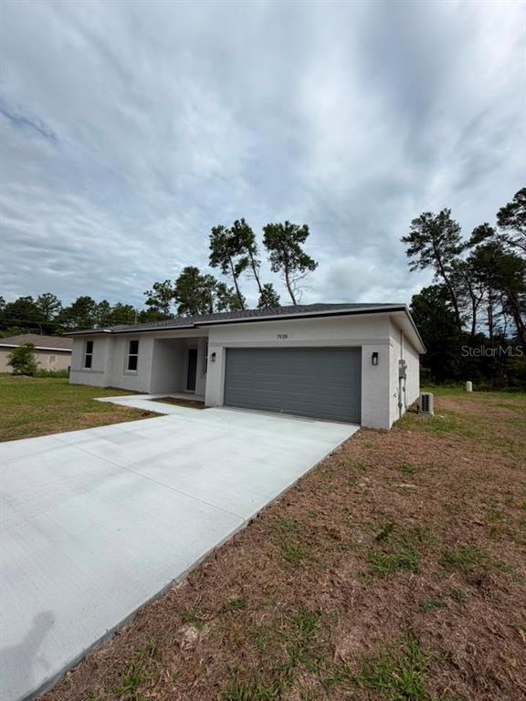 A single-story house with a gray garage door, white exterior, and a concrete driveway — 7939 SW 141ST PLACE, OCALA, FL