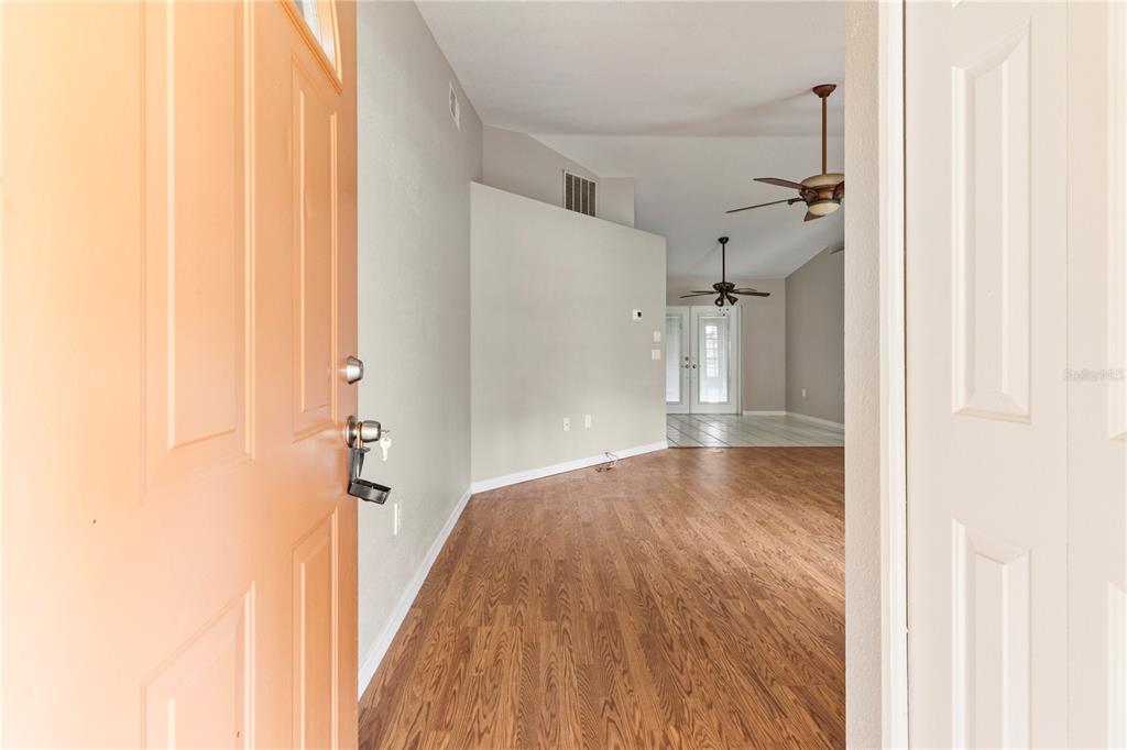 An entryway with wood-look flooring opens into a living area with a vaulted ceiling — 3351 TUCSON ROAD, NORTH PORT, FL