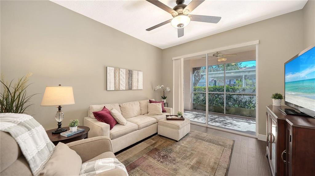 A living room features a beige sofa, an armchair, a ceiling fan, and sliding glass doors — 4224 CENTRAL SARASOTA PARKWAY UNIT 1116, SARASOTA, FL