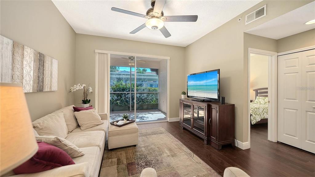 A living room features a beige sofa, a television on a console, and a sliding door — 4224 CENTRAL SARASOTA PARKWAY UNIT 1116, SARASOTA, FL